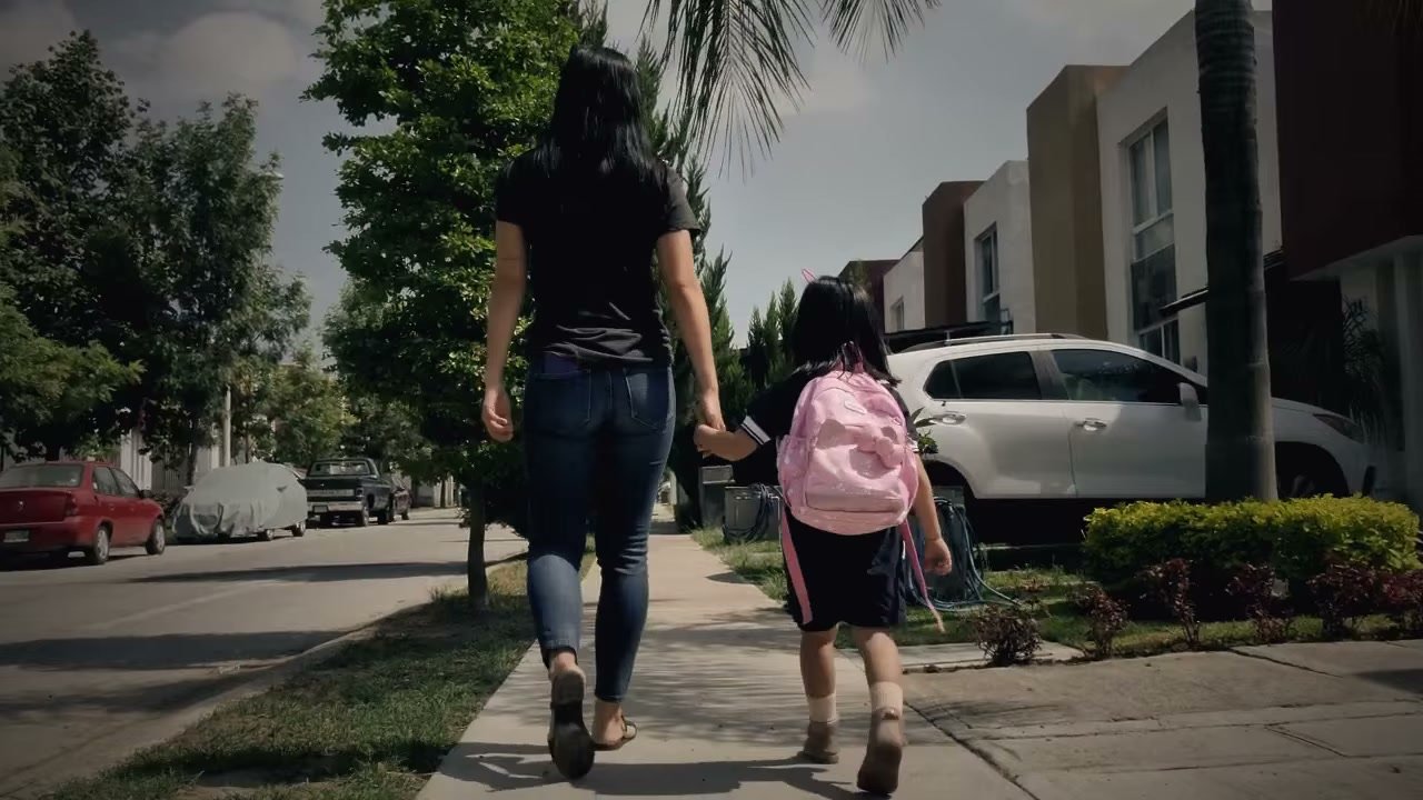 A mother and daughter walking down a neighborhood sidewalk